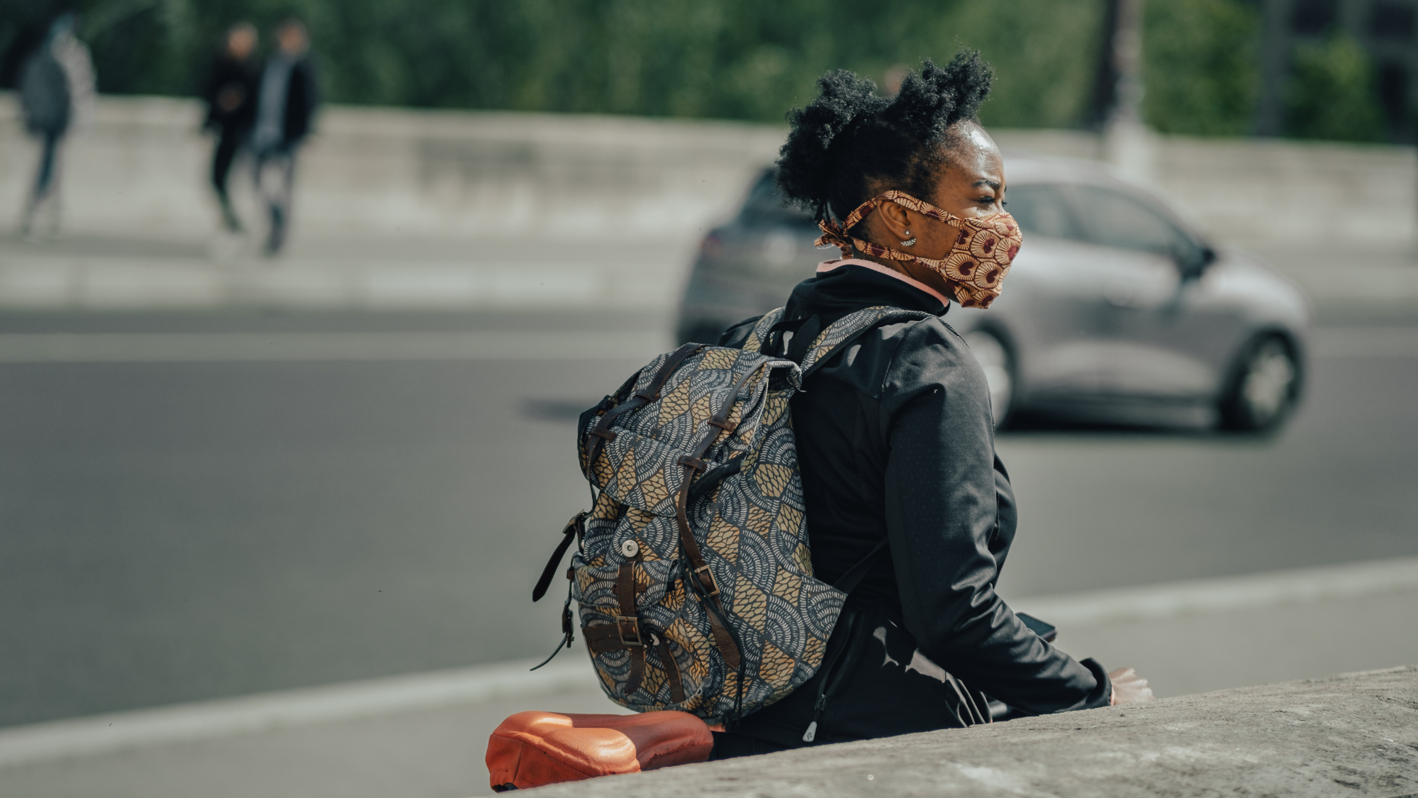 Lady on a bike wearing a mask taking the time to observe her surroundings. Thanks to Thomas de LUZE for sharing their work on Unsplash.