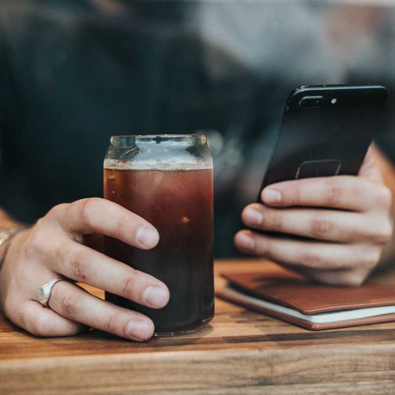 Person writing on iPhone next to coffee